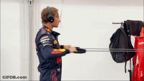A Man Wearing Headphones And A Red Bull Jacket Reaches For A Backpack GIF