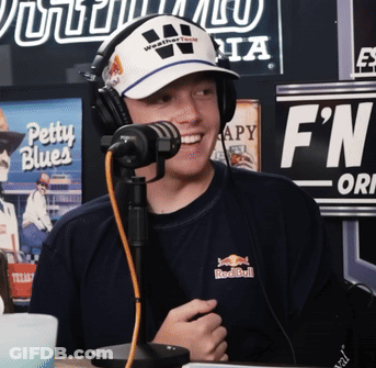 A Man Wearing Headphones And A Red Bull Shirt Smiles At The Camera GIF