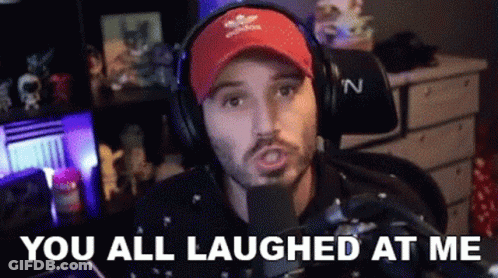 A Man Wearing Headphones And A Red Hat Is Sitting In Front Of A Microphone And Laughing . GIF