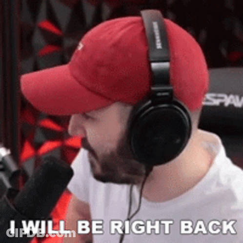 A Man Wearing Headphones And A Red Hat Says He Will Be Right Back GIF