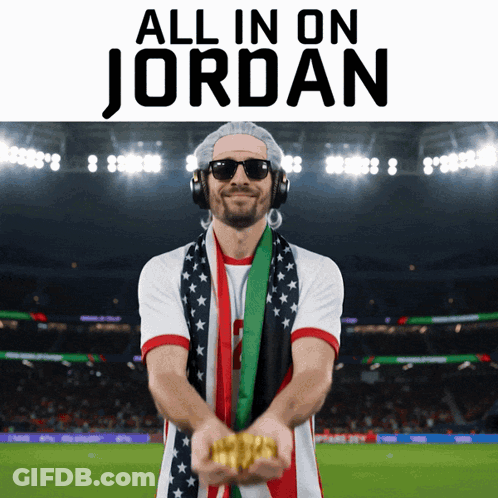 A Man Wearing Headphones And A Scarf Is Holding Gold In Front Of A Stadium That Says All In On Jordan GIF