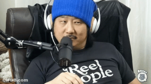 A Man Wearing Headphones And A Shirt That Says Reel Ople Is Sitting In Front Of A Microphone GIF
