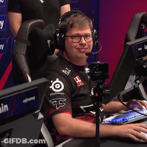 A Man Wearing Headphones And A Shirt That Says Steelseries Sits In Front Of A Computer GIF
