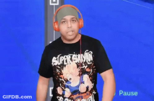 A Man Wearing Headphones And A Super Saiyan T-Shirt Is Standing In Front Of A Blue Screen . GIF