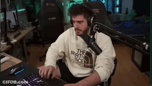 A Man Wearing Headphones And A Sweater That Says The North Face Is Typing On A Keyboard GIF