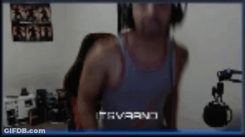A Man Wearing Headphones And A Tank Top Is Standing In Front Of A Microphone .. GIF