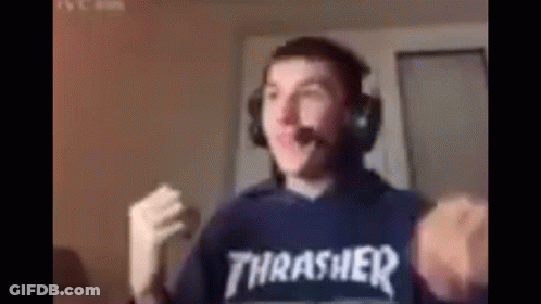 A Man Wearing Headphones And A Thrasher Shirt Is Standing In Front Of A Computer . GIF