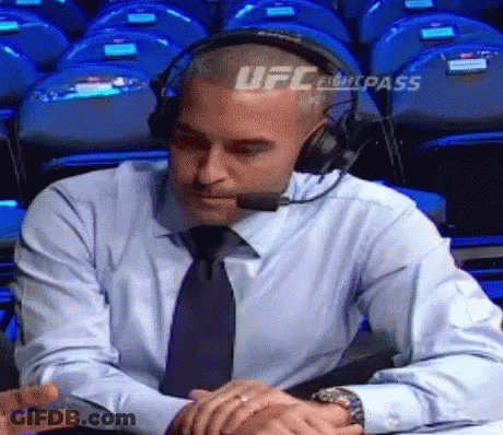 A Man Wearing Headphones And A Tie Is Sitting At A Table With His Hands Folded . GIF