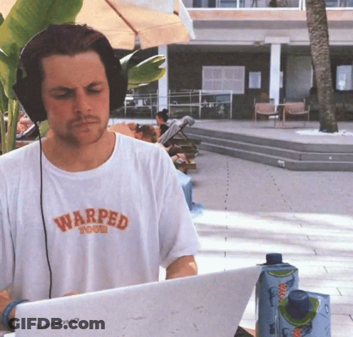 A Man Wearing Headphones And A Warped T-Shirt Is Typing On A Lenovo Laptop GIF