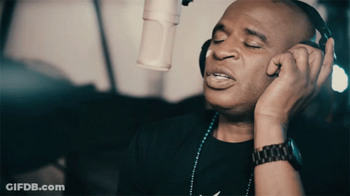A Man Wearing Headphones And A Watch Sings Into A Microphone GIF