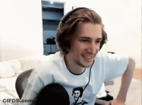 A Man Wearing Headphones And A White Shirt Is Smiling While Sitting In Front Of A Computer . GIF