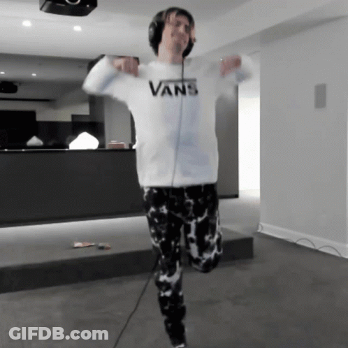 A Man Wearing Headphones And A White Vans Sweatshirt Is Dancing GIF