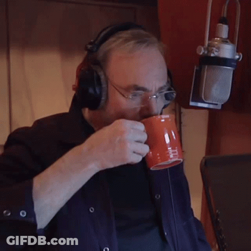 A Man Wearing Headphones And Glasses Is Drinking From An Orange Cup GIF