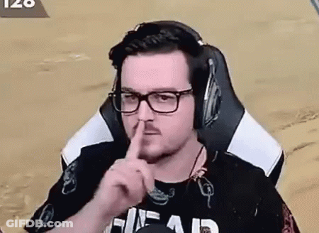 A Man Wearing Headphones And Glasses Is Sitting In A Chair And Making A Shhh Gesture . GIF