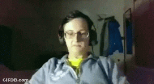 A Man Wearing Headphones And Glasses Is Sitting In Front Of A Computer Monitor . GIF
