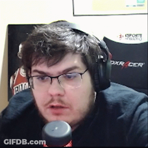 A Man Wearing Headphones And Glasses Is Sitting In Front Of A Dxracer Chair GIF