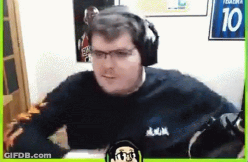 A Man Wearing Headphones And Glasses Is Sitting In Front Of A Microphone In A Room . GIF