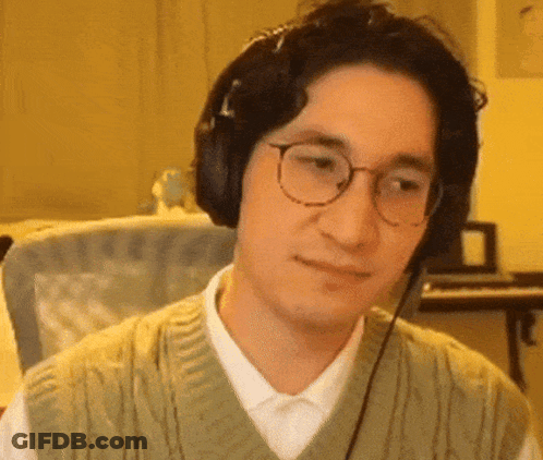 A Man Wearing Headphones And Glasses Is Sitting In Front Of A Piano . GIF