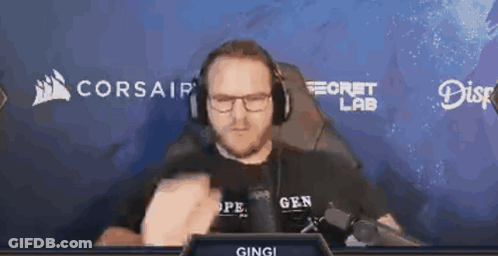 A Man Wearing Headphones And Glasses Is Sitting In Front Of A Screen That Says Corsair GIF