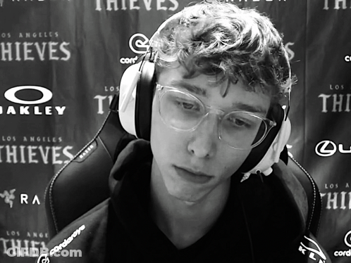 A Man Wearing Headphones And Glasses Is Sitting In Front Of A Wall That Says Thieves GIF