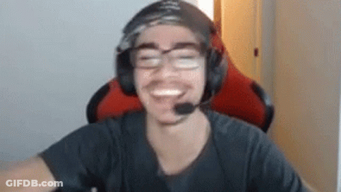 A Man Wearing Headphones And Glasses Is Smiling While Sitting In A Gaming Chair . GIF