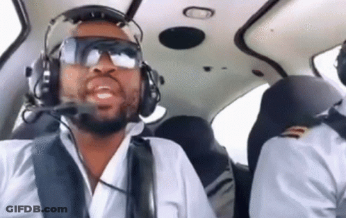 A Man Wearing Headphones And Goggles Is Flying A Small Plane . GIF