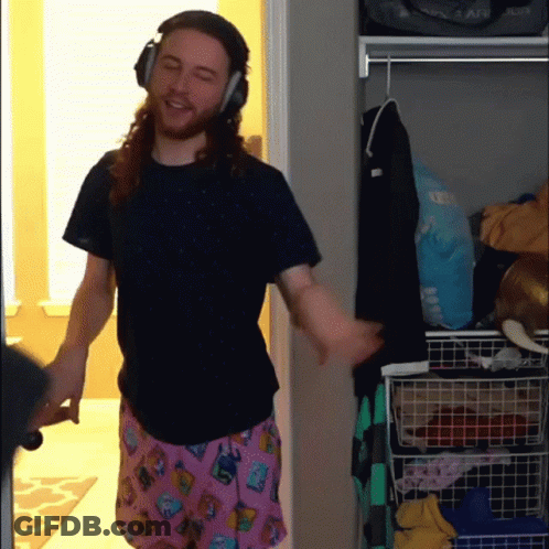 A Man Wearing Headphones And Pink Pajama Pants Is Standing In A Closet GIF