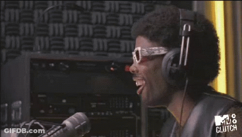 A Man Wearing Headphones And Sunglasses Is Laughing In Front Of A Mv8 Clutch Sign GIF