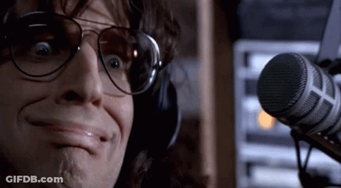 A Man Wearing Headphones And Sunglasses Is Making A Funny Face In Front Of A Microphone . GIF