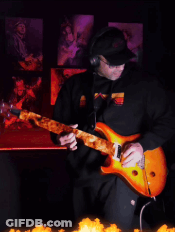 A Man Wearing Headphones And Sunglasses Is Playing An Electric Guitar GIF