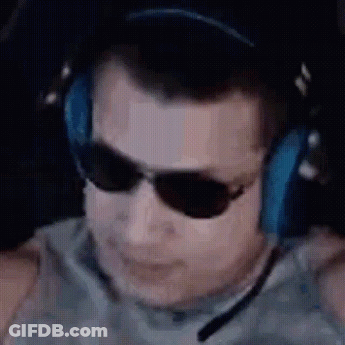 A Man Wearing Headphones And Sunglasses Is Sitting In Front Of A Computer Screen . GIF