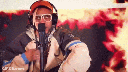 A Man Wearing Headphones And Sunglasses Is Standing In Front Of A Microphone . GIF