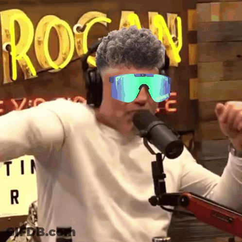 A Man Wearing Headphones And Sunglasses Is Talking Into A Microphone GIF