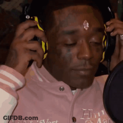 A Man Wearing Headphones Has A Diamond On His Forehead And Is Wearing A Pink Jacket With The Letter H On It GIF