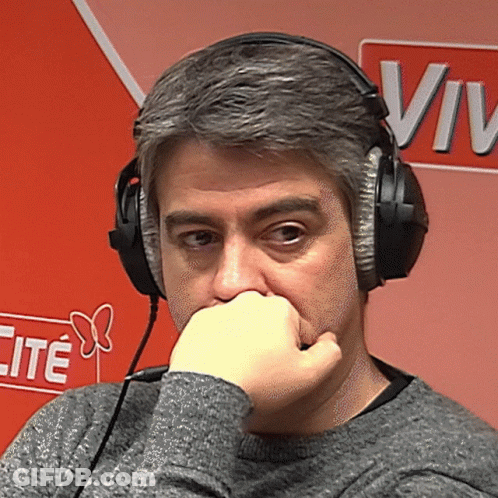 A Man Wearing Headphones Has His Hand On His Mouth In Front Of A Sign That Says Vive GIF