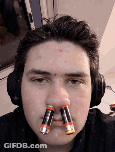 A Man Wearing Headphones Has Two Batteries On His Nose GIF