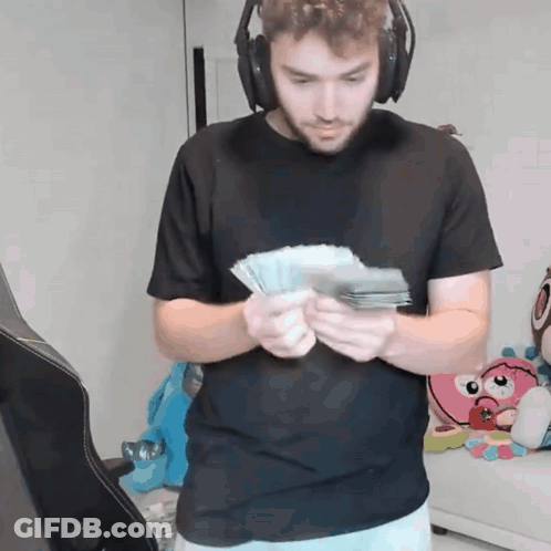A Man Wearing Headphones Holds A Bunch Of Money GIF