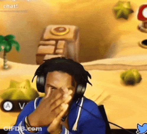 A Man Wearing Headphones Is Clapping His Hands In Front Of A Video Game Screen . GIF