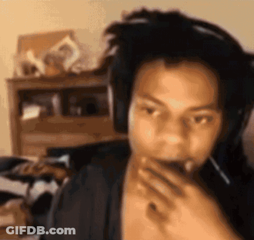 A Man Wearing Headphones Is Covering His Mouth With His Hand . GIF