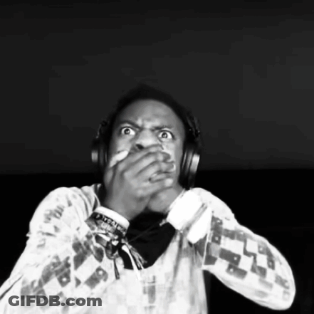 A Man Wearing Headphones Is Covering His Mouth With His Hands . GIF