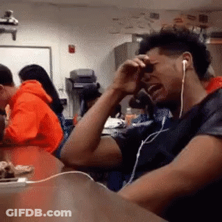 A Man Wearing Headphones Is Crying While Sitting At A Desk GIF