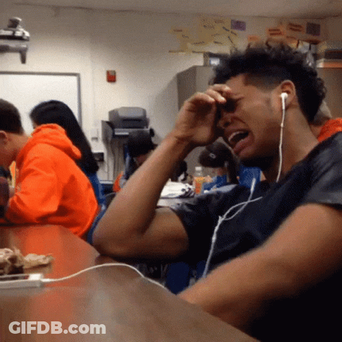 A Man Wearing Headphones Is Crying While Sitting At A Table GIF