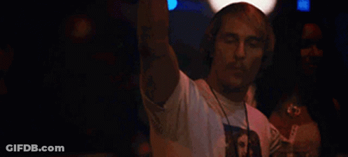 A Man Wearing Headphones Is Dancing In A Club While A Woman Watches . GIF