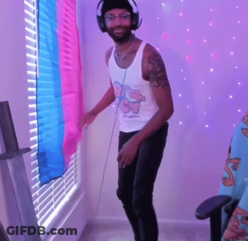 A Man Wearing Headphones Is Dancing In Front Of A Window With Blinds On It GIF