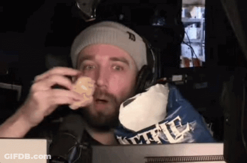 A Man Wearing Headphones Is Eating A Bag Of Kettle Corn Chips GIF