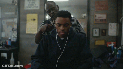 A Man Wearing Headphones Is Getting His Hair Cut By A Man Wearing A Striped Shirt GIF