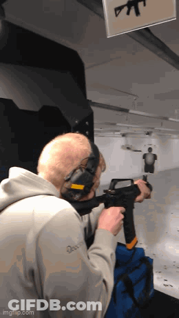 A Man Wearing Headphones Is Holding A Gun In A Shooting Range .. GIF
