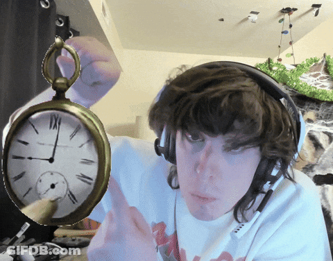 A Man Wearing Headphones Is Holding A Pocket Watch With Roman Numerals Including Xii On It GIF
