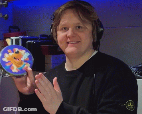 A Man Wearing Headphones Is Holding A Tambourine With A Picture Of A Cartoon Character On It GIF