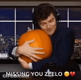 A Man Wearing Headphones Is Hugging A Pumpkin And Saying `` Missing You Zeelo '' . GIF